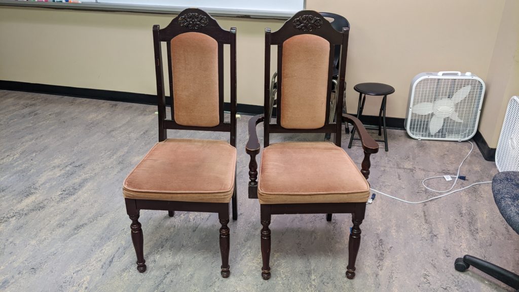 Two pinkish padded chairs, one with arms and one without